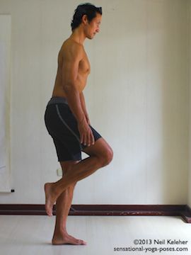 balancing on one leg and slowly bending forwards while keeping the lifted knee pulled forwards. This photo shows the starting position with knee lifted and torso upright. Neil Keleher. Sensational Yoga Poses.