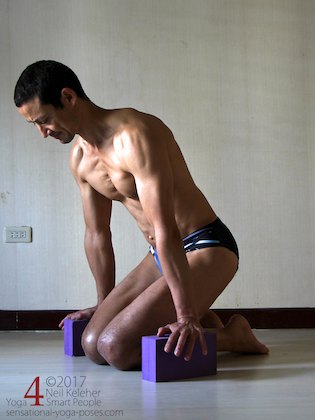 Bending forwards while kneeling with hands pressing down onto yoga blocks to support weight of your body while working towards a kneeling quadriceps stretch. Neil Keleher. Sensational Yoga Poses.