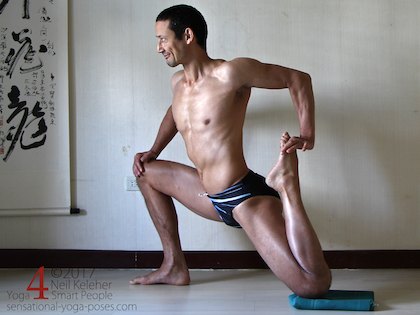 Lunging bent knee hip flexor stretching yoga pose, pushing the foot forwards with the hand (as opposed to pulling it). Neil Keleher. Sensational Yoga Poses.