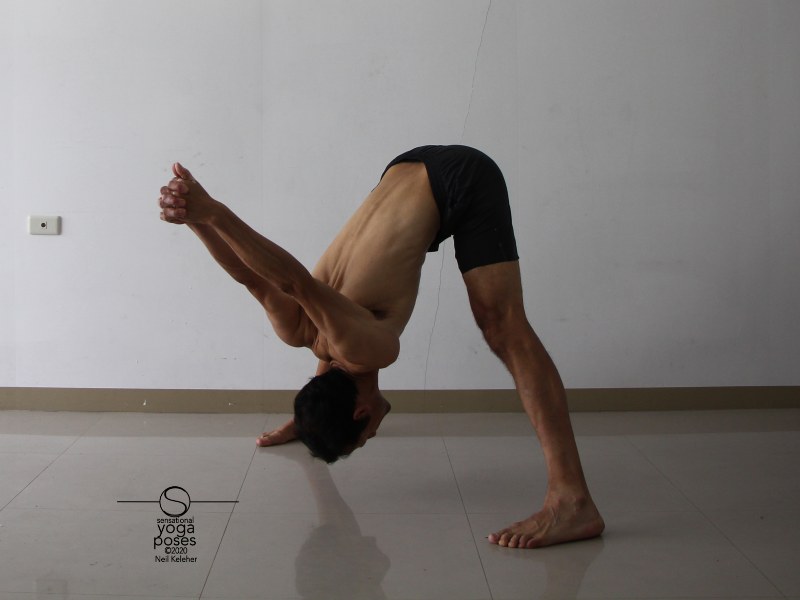 Wide leg standing hamstring stretch with hands clasped behind back (prasaritta padotanasana c). Bending forwards, keep your chest contracted towards your hip bones. Try lifting your sitting bones or pulling down on your ASICs to stretch your hamstrings. Neil Keleher, Sensational Yoga Poses.