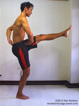 Sensational Yoga Poses, Model Neil Keleher. Balancing on one leg with the other knee lifted. In this execise stand on one leg with the foot turned out and the knee slightly bent. Pull the lower belly in. Pull the pubic bone up. Lift the chest. Then lift the knee of the unsupported leg. Then straighten the knee. In this picture weight is on one leg, the other leg is lifed with the lifted knee straight and the foot reaching straight ahead. Lower belly is pulled in, pubic bone lifted and chest lifted. This is a preparation for the balancing on one leg pose utthitta hasta padangusthasana.
